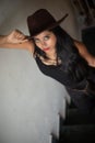 Lifestyle images of young Indian sexy girl in black western dress and cowboy hat on the landing of a staircase with railings