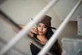 Lifestyle images of young Indian sexy girl in black western dress and cowboy hat on the landing of a staircase with railings