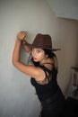 Lifestyle images of young Indian sexy girl in black western dress and cowboy hat on the landing of a staircase with railings