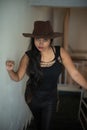 Lifestyle images of young Indian sexy girl in black western dress and cowboy hat on the landing of a staircase with railings as