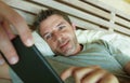 Lifestyle indoors portrait of young happy and attractive man at home bedroom using internet social media app networking from bed s Royalty Free Stock Photo