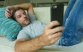 Lifestyle indoors portrait of young happy and attractive man at home sofa couch using internet social media app on mobile phone ne Royalty Free Stock Photo
