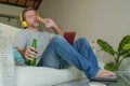 Young happy relaxed and attractive man sitting at home sofa couch with headset and laptop listening to internet music online enjoy Royalty Free Stock Photo