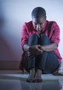 Lifestyle indoors portrait of young sad and depressed black african American woman sitting at home floor feeling desperate and wor Royalty Free Stock Photo
