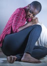 Lifestyle indoors portrait of young sad and depressed black afro American woman sitting at home floor feeling desperate and worrie Royalty Free Stock Photo