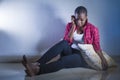 Lifestyle indoors portrait of young sad and depressed black afro American woman sitting at home floor feeling desperate and worrie Royalty Free Stock Photo