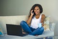 Lifestyle isolated portrait of young happy and gorgeous black african American woman talking on mobile phone while working on lapt Royalty Free Stock Photo