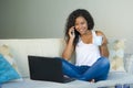 Lifestyle isolated portrait of young happy and gorgeous black african American woman talking on mobile phone while working on lapt Royalty Free Stock Photo