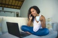 Lifestyle isolated portrait of young happy and gorgeous black afro American woman talking on mobile phone while working on laptop Royalty Free Stock Photo