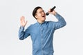 Lifestyle, leisure and people concept. Carefree asian guy in glasses and braces singing song at karaoke bar, holding Royalty Free Stock Photo