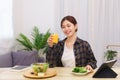 Lifestyle in living room concept, Asian woman drinking orange juice and eating vegetable salad Royalty Free Stock Photo