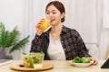 Lifestyle in living room concept, Asian woman drinking orange juice and eating vegetable salad Royalty Free Stock Photo