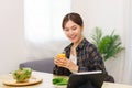 Lifestyle in living room concept, Asian woman watching movie on tablet and drinking orange juice Royalty Free Stock Photo