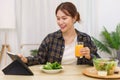 Lifestyle in living room concept, Young Asian woman pointing on tablet and drinking orange juice Royalty Free Stock Photo