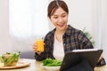 Lifestyle in living room concept, Young Asian woman pointing on tablet and drinking orange juice Royalty Free Stock Photo