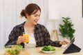 Lifestyle in living room concept, Young Asian woman pointing on tablet and drinking orange juice Royalty Free Stock Photo