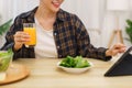 Lifestyle in living room concept, Young Asian woman pointing on tablet and drinking orange juice Royalty Free Stock Photo