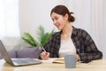 Lifestyle in living room concept, Young Asian woman using laptop and taking notes data on notebook Royalty Free Stock Photo