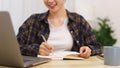 Lifestyle in living room concept, Young Asian woman using laptop and taking notes data on notebook Royalty Free Stock Photo