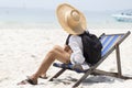 Lifestyle man wears straw hat and sitting on deck chair on the beach