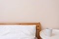 Lifestyle minimal bedroom interior detail, bed with white pillow. coffee cup on bedside table, empty peachy neutral wall Royalty Free Stock Photo