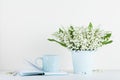 Lifestyle mockup decorated flowers in vase and coffee cup with notebook on white table with clean space for text and design. Royalty Free Stock Photo