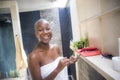 Lifestyle natural portrait of young happy and attractive internet addict afro American woman in home bathroom wrapped in towel usi Royalty Free Stock Photo