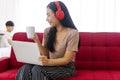 Lifestyle new normal concept. Joyful woman wearing wireless headphones using laptop playlist listens music while holding cup