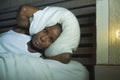 Lifestyle night portrait of young desperate and stressed black afro American woman lying on bed upset trying to sleep suffering he Royalty Free Stock Photo