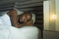 Lifestyle night portrait of young sad and stressed black african American woman lying on bed upset trying to sleep suffering insom Royalty Free Stock Photo