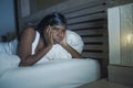 Night portrait of young sad and worried black afro American woman in bed at home sleepless and stressed feeling depressed sufferin Royalty Free Stock Photo
