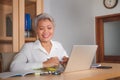 Lifestyle office portrait of attractive and happy successful middle aged Asian woman working at laptop computer desk smiling Royalty Free Stock Photo