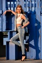 Lifestyle outdoor image of attractive young stylish woman posing in front of wooden background.