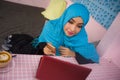 Young beautiful and happy woman in muslim hijab head scarf working with laptop computer and mobile phone networking running inter Royalty Free Stock Photo