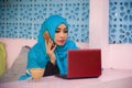 Young beautiful and happy woman in muslim hijab head scarf working with laptop computer and mobile phone networking running inter Royalty Free Stock Photo