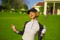 Lifestyle outdoors portrait of young beautiful and happy woman at playing golf holding ball and putter club smiling cheerful in st