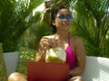 Lifestyle outdoors portrait of young happy and attractive Asian Indonesian teenager girl in bikini networking with laptop computer Royalty Free Stock Photo