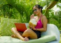 Lifestyle outdoors portrait of young happy and attractive Asian Indonesian teenager girl in bikini networking with laptop computer Royalty Free Stock Photo