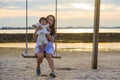 Young sweet and happy Asian Chinese woman holding baby girl swinging together at beach swing on Summer sunset in mother and little Royalty Free Stock Photo