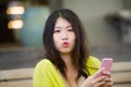 Lifestyle outdoors urban portrait of young attractive and beautiful Asian Japanese woman enjoying using internet social media app Royalty Free Stock Photo