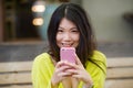 Lifestyle outdoors urban portrait of young attractive and beautiful Asian Japanese woman enjoying using internet social media app Royalty Free Stock Photo