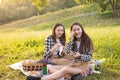 Lifestyle in the Park in summer. Girls with a picnic basket sitting on the grass, laughing