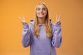 Peaceful glad attractive blond european young female college student in hoodie smiling friendly make peace victory