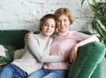 Lifestyle and people concept - Beautiful senior mom and her adult daughter are hugging, looking at camera and smiling. Royalty Free Stock Photo