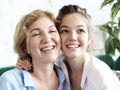 Lifestyle and people concept - beautiful senior mom and her adult daughter are hugging, looking at camera and smiling. Royalty Free Stock Photo