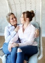 Mature motherand daughter hugging each other in armchair. Royalty Free Stock Photo