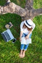 Lifestyle person Girl enjoy listening music and reading a book and play laptop on the grass field of the nature park in the mornin