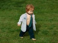 Lifestyle portrait baby child in happines at the outside in the meadow. Happy baby boy learning to walk on grass Royalty Free Stock Photo