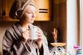 Lifestyle portrait of a beautiful young girl drinking morning coffee in her kitchen Royalty Free Stock Photo