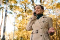 Lifestyle portrait of a business woman, pretty lady talking on mobile phone while walking on the autumnal park, enjoying beautiful Royalty Free Stock Photo